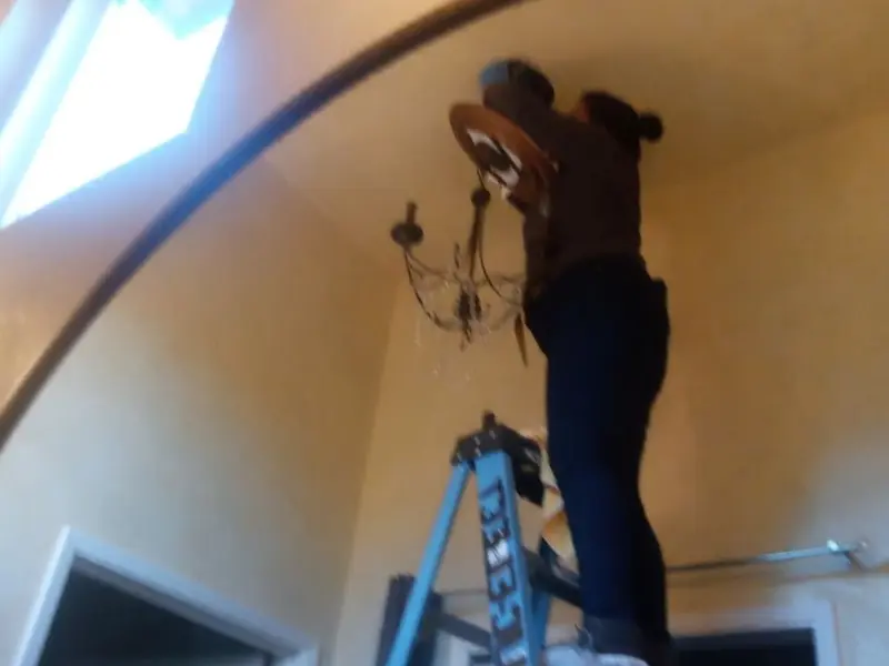 Electrician installing a chandelier in a Spring City residence